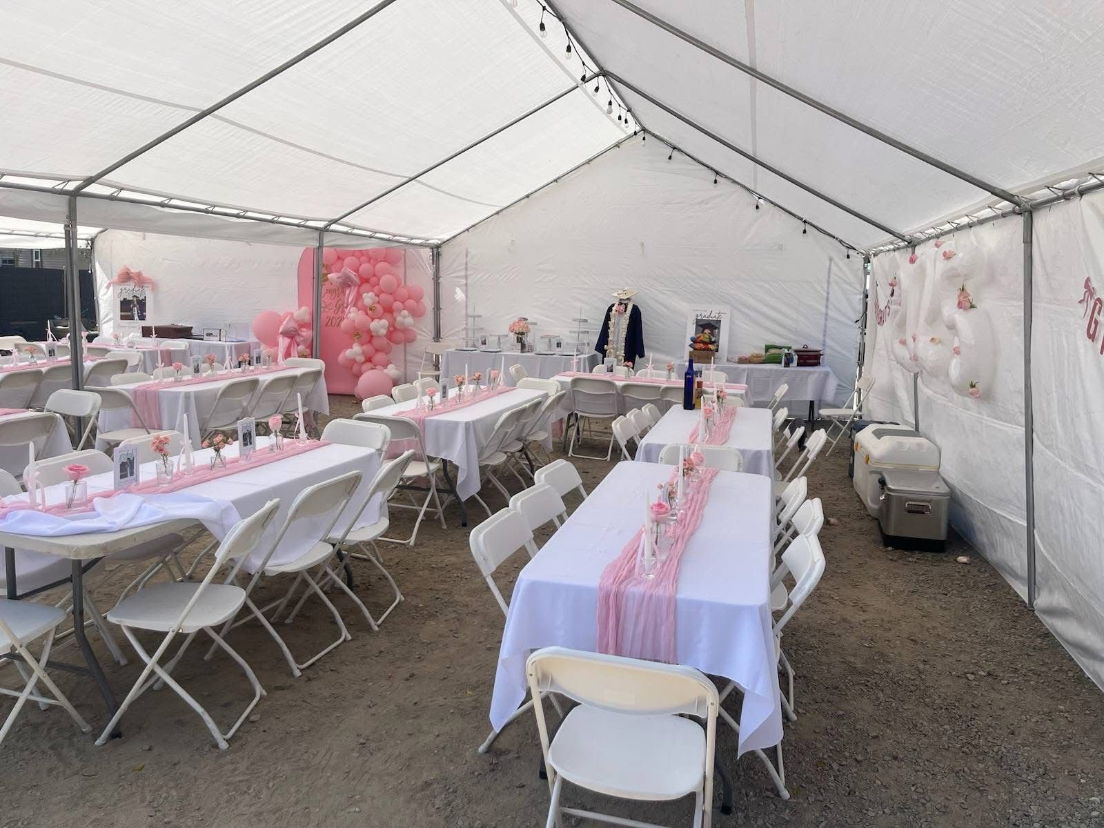 Party tables and white chairs arranged inside a tent