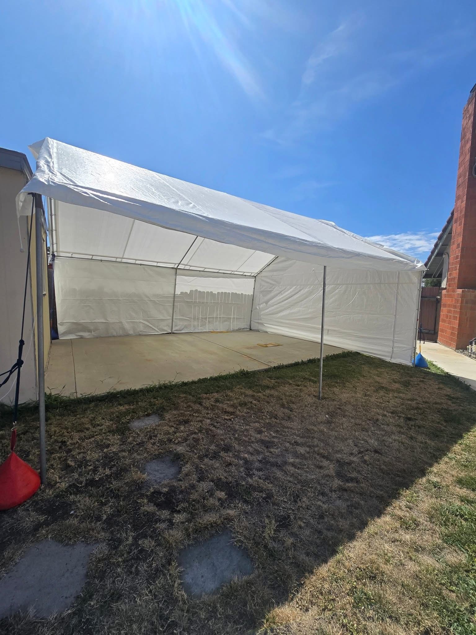 Residential white tent installed beside a home