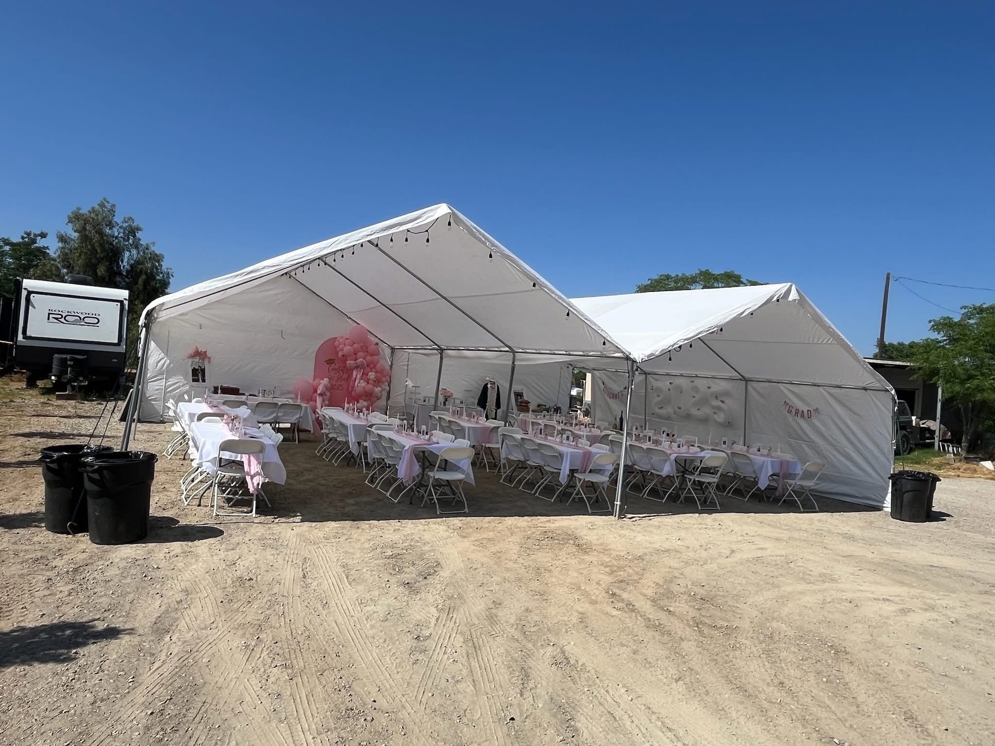Large white party tents with tables and chairs set up for an event